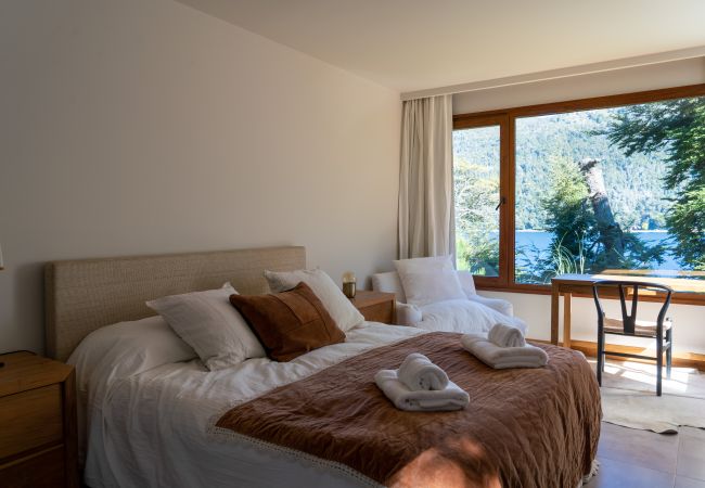 Master bedroom in Arrayán 1A apartment with double bed, workspace desk, and lake views.